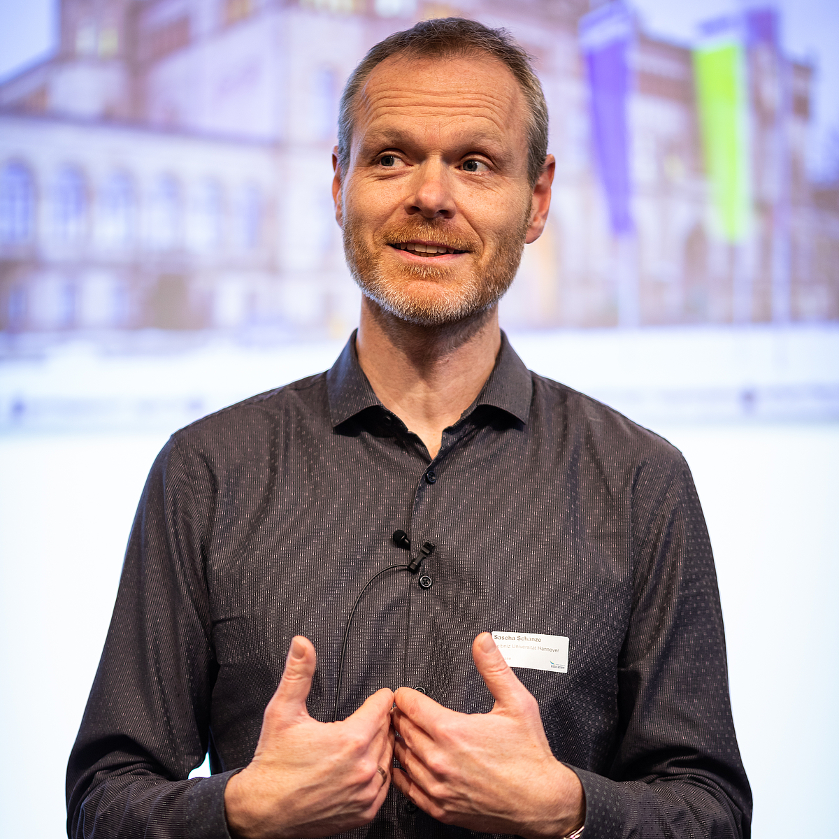 Professor Sascha Schanze eröffnet die Didaktische Werkstatt vor dem Publikum im Saal des renovierten Pferdestalls.